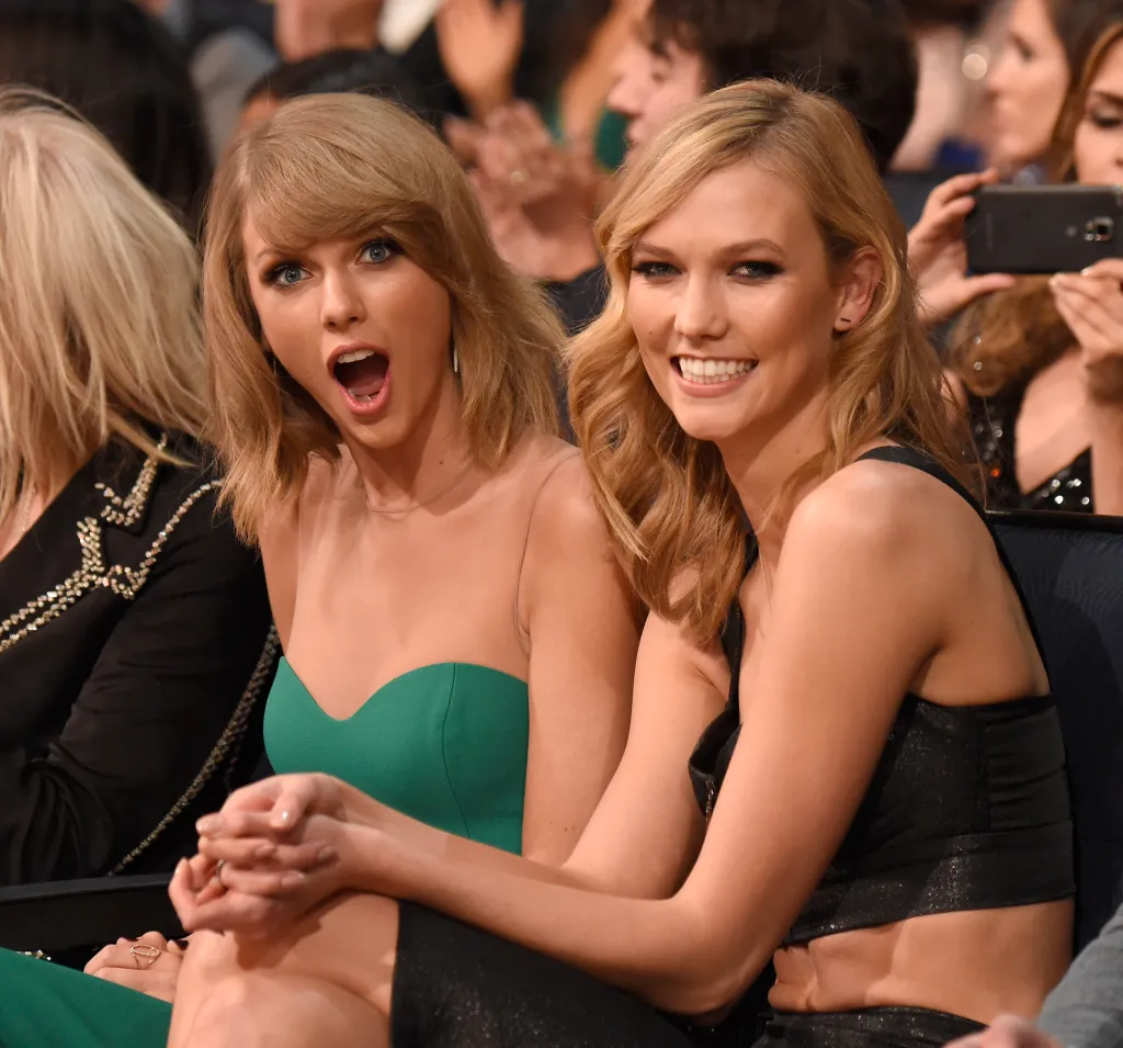Taylor Swift with her mouth open and Karlie Kloss smiling.