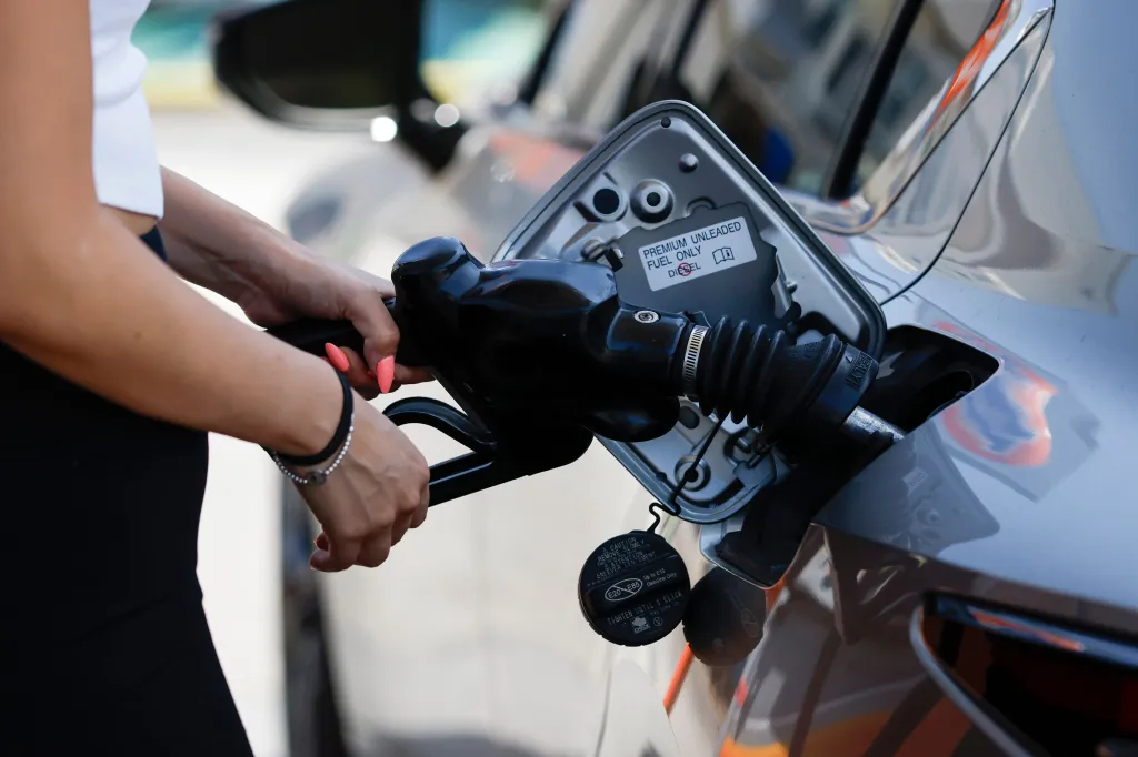 A person pumping gasoline into a car at a 76 gasoline station.