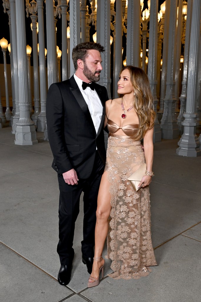 Ben Affleck in a black tuxedo and Jennifer Lopez in a gold gown with a high slit, posing together at the 2023 LACMA Art+Film Gala.