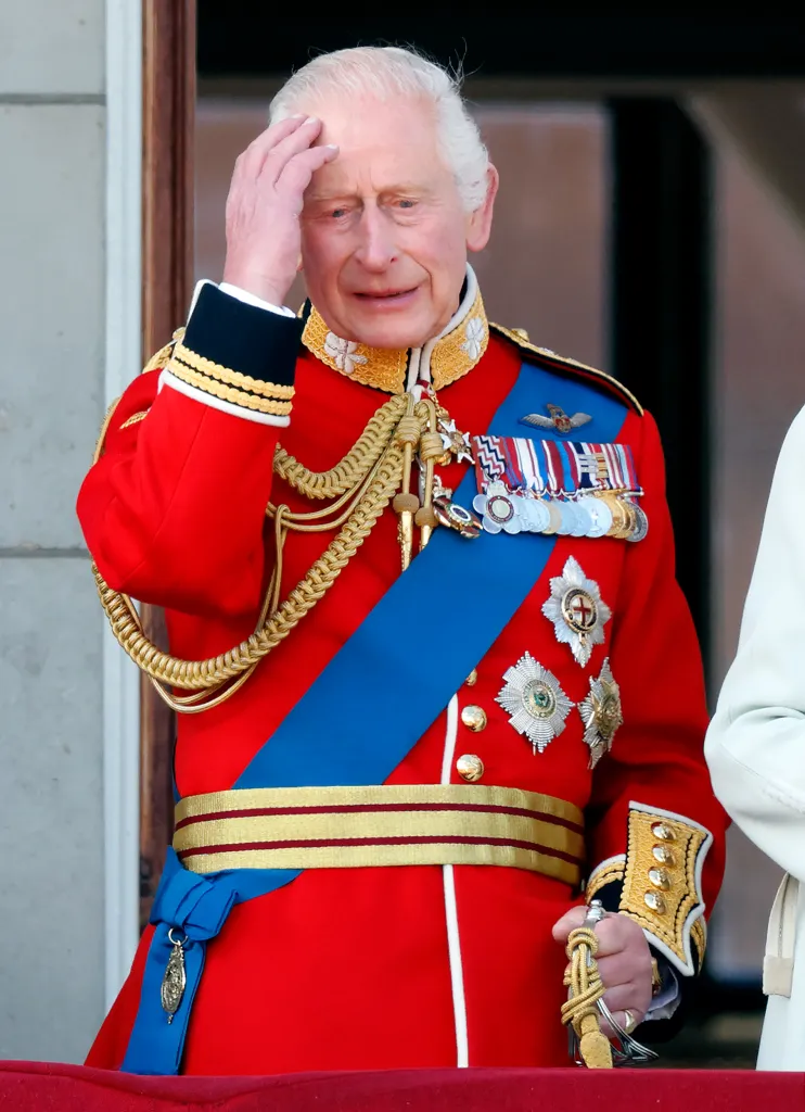 King Charles III in red Irish Guards uniform with hand to his head at Trooping the Colour.