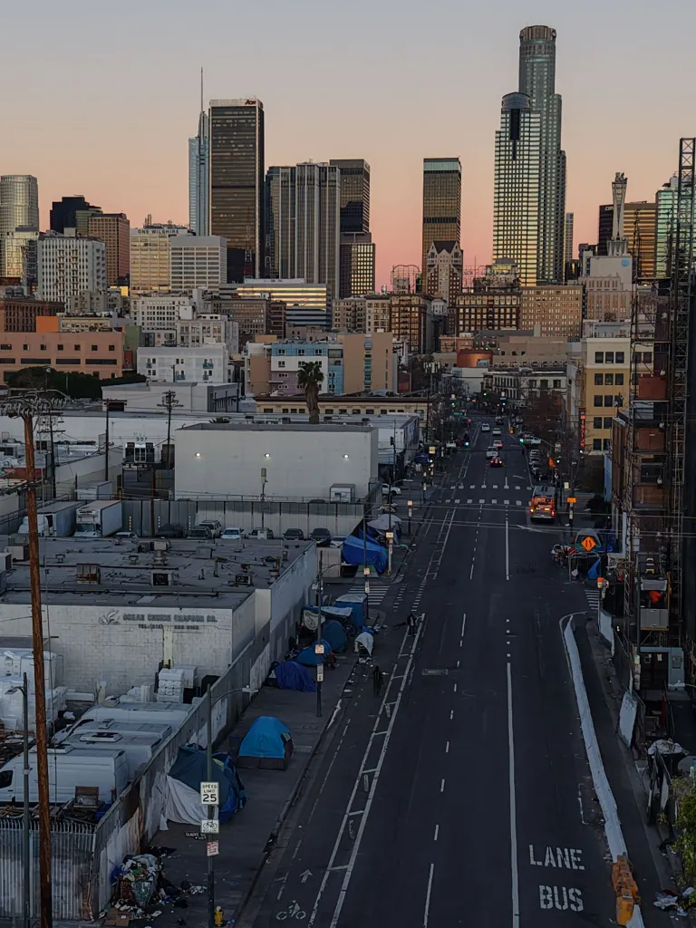 Homeless encampments in Downtown Los Angeles with the city skyline in the background.