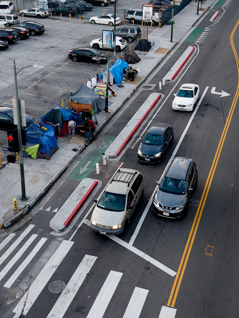 Aerial view of a Los Angeles street with homeless encampments and cars.