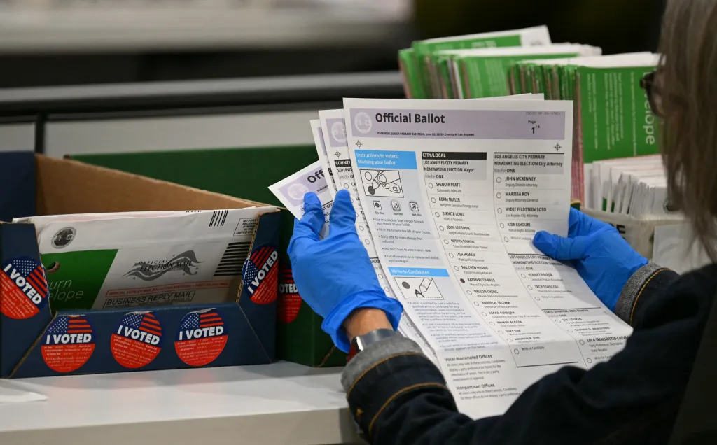 An election worker in blue gloves holds up an official ballot in a vote tabulation center.