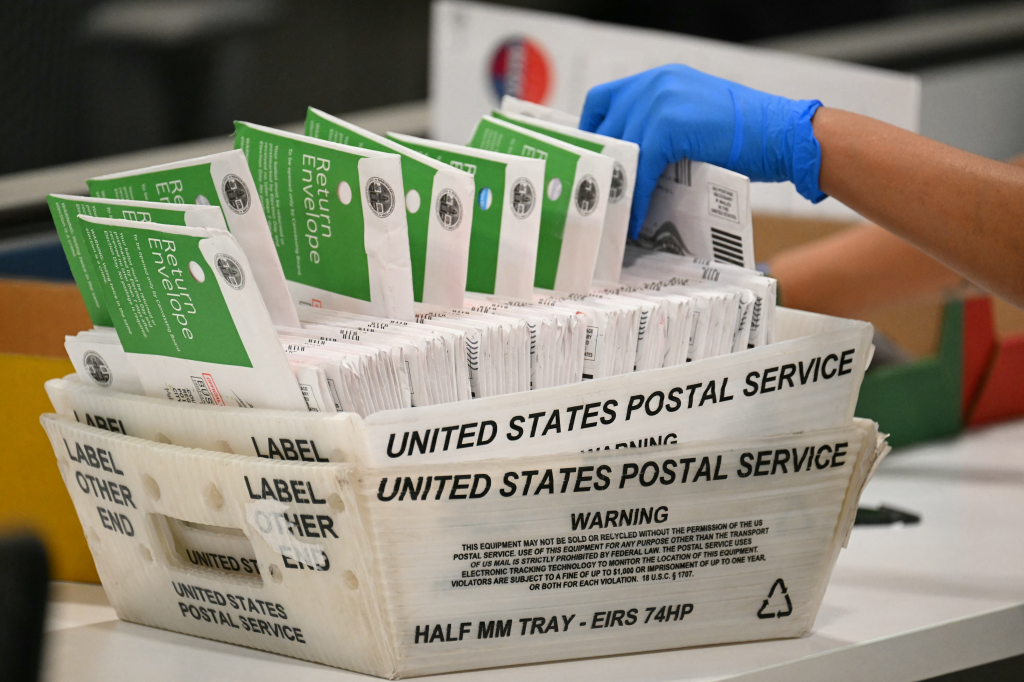 An election worker wearing a blue glove processes mail-in ballots in Los Angeles, California.