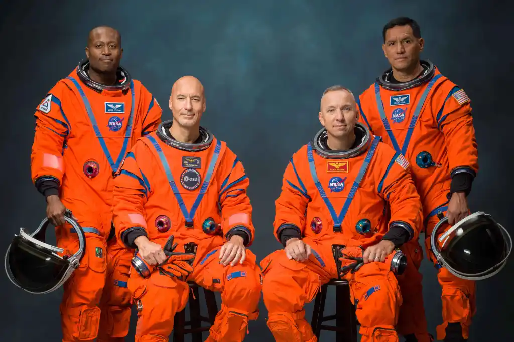 The four-member Artemis III crew, Andre Douglas, Luca Parmitano, Randy Bresnik, and Frank Rubio, pose in orange space suits.