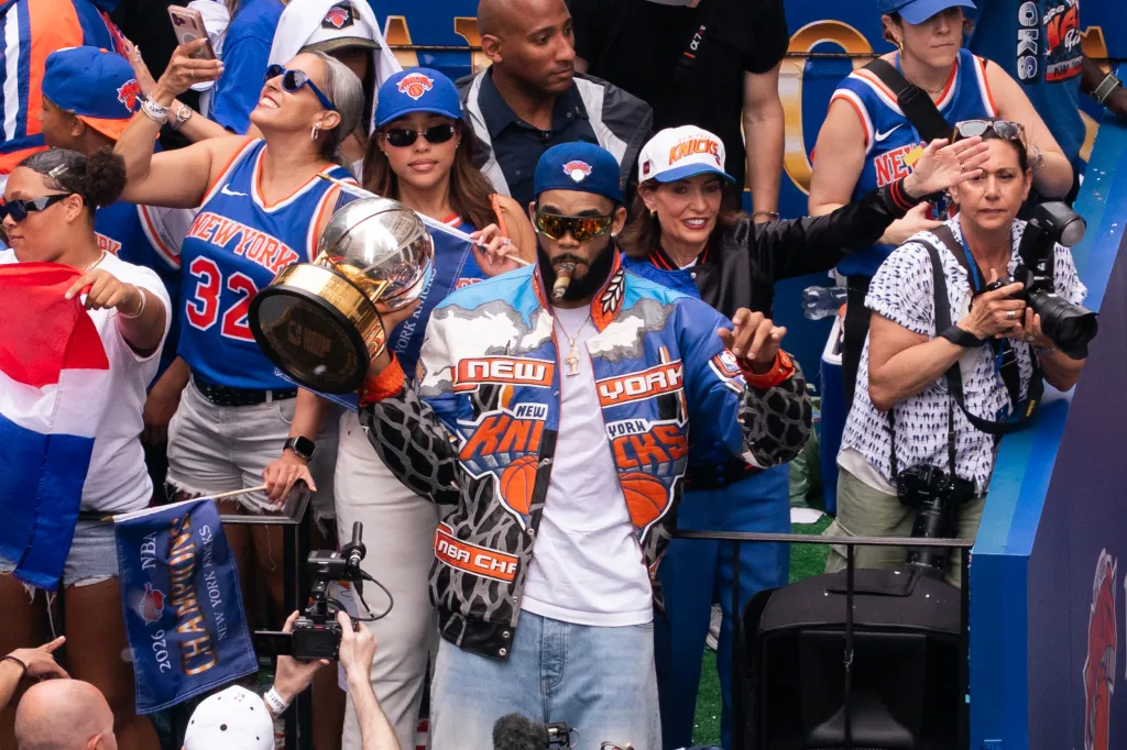 Karl-Anthony Towns of the New York Knicks smoking a cigar and holding the championship trophy during the Championship ticker-tape parade.