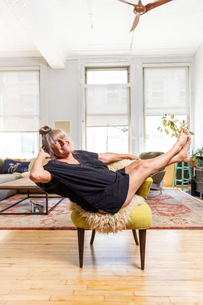 Robin Byrd relaxing on a chartreuse chair with her legs crossed and feet elevated.