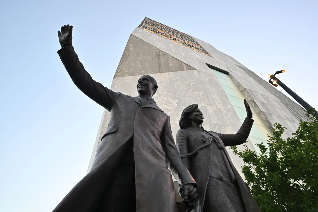 A low-angle view of a bronze statue depicting former US President Barack Obama and former First Lady Michelle Obama waving stands outside the main museum tower prior to the Barack Obama Presidential Center's Grand Opening Ceremony held at the Center's John Lewis Plaza in Chicago, Illinois, USA, 18 June 2026.