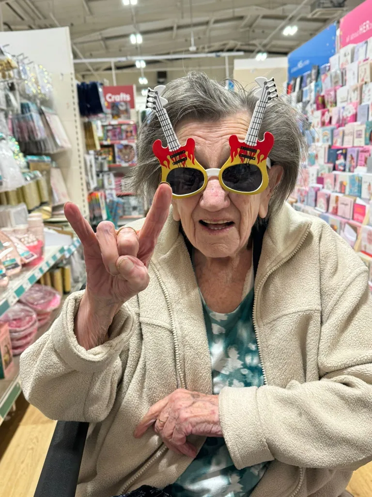 A woman wearing guitar-shaped sunglasses gives the rock and roll hand sign.