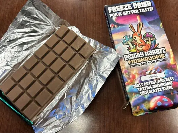 Psilocybin chocolate bar in foil next to its colorful "Psilly Rabbit Mushrooms" packaging.