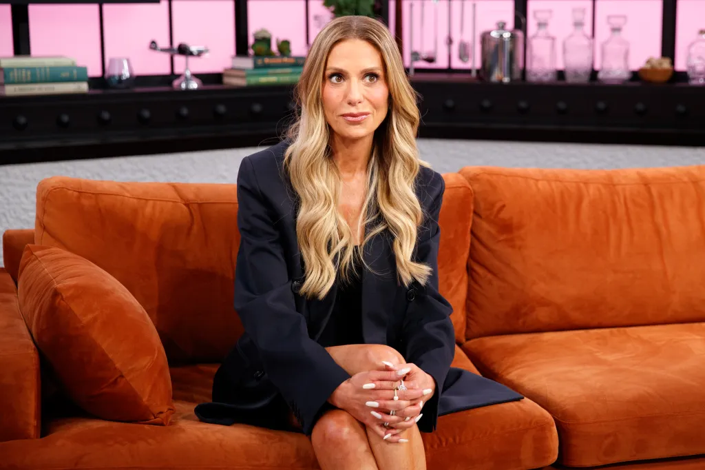 Dorit Kemsley sitting on an orange sofa, wearing a dark blue blazer.