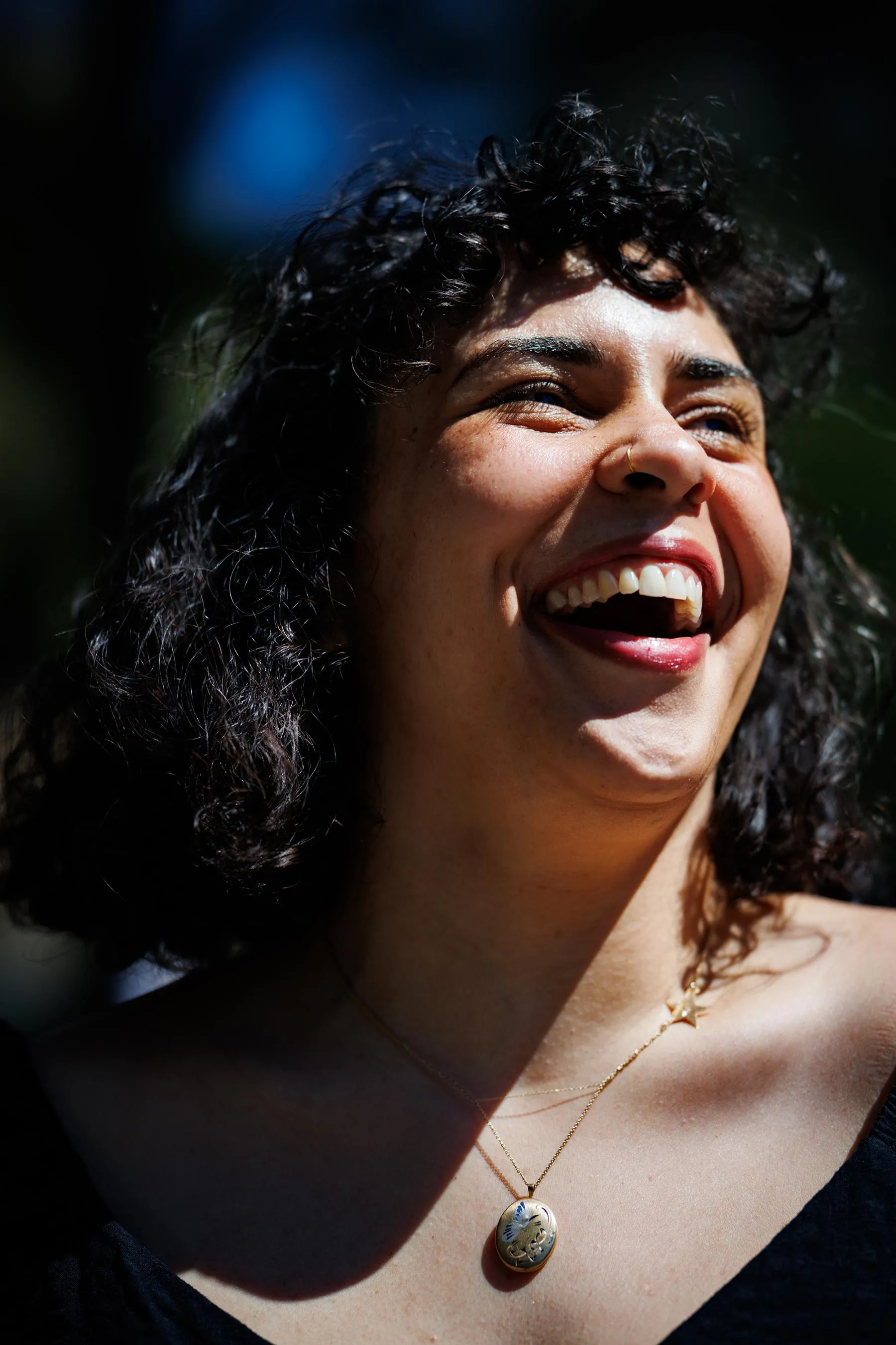a woman is outside, laughing while squinting in the sunlight a woman is outside, laughing while squinting in the sunlight