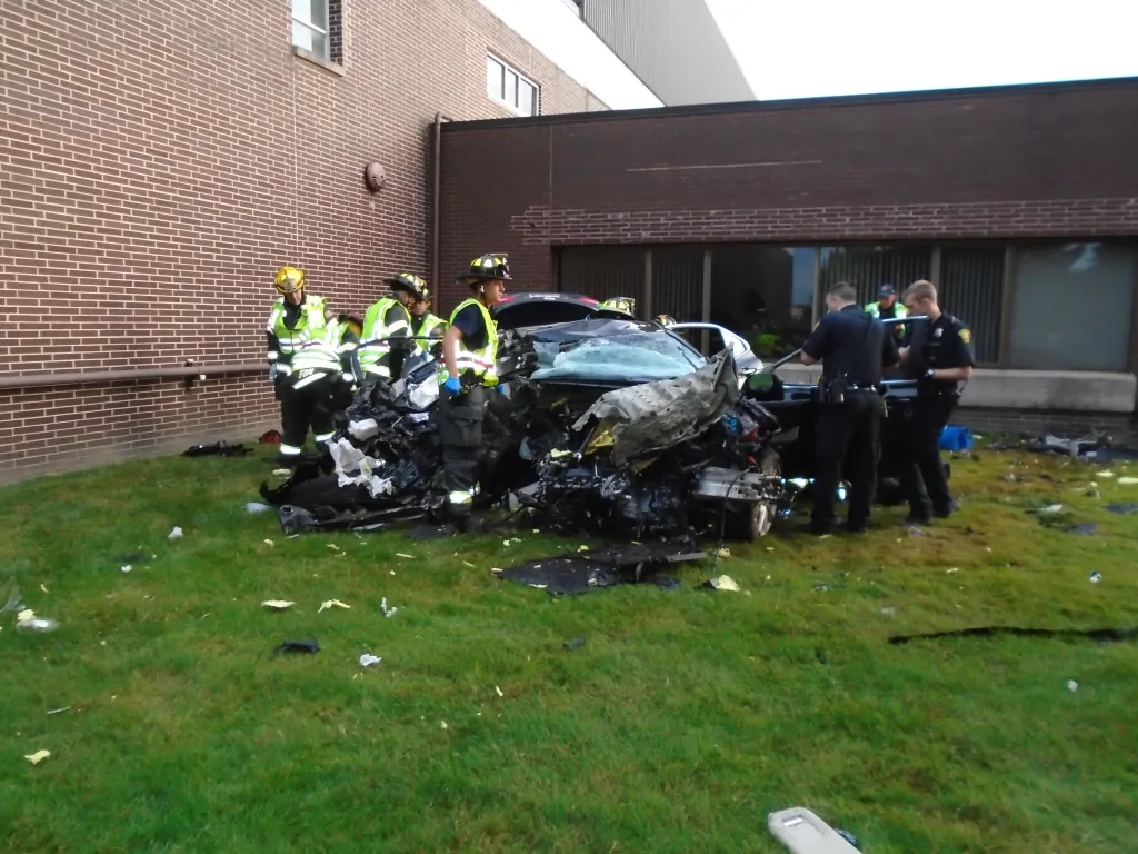Emergency responders gathered around a demolished car.