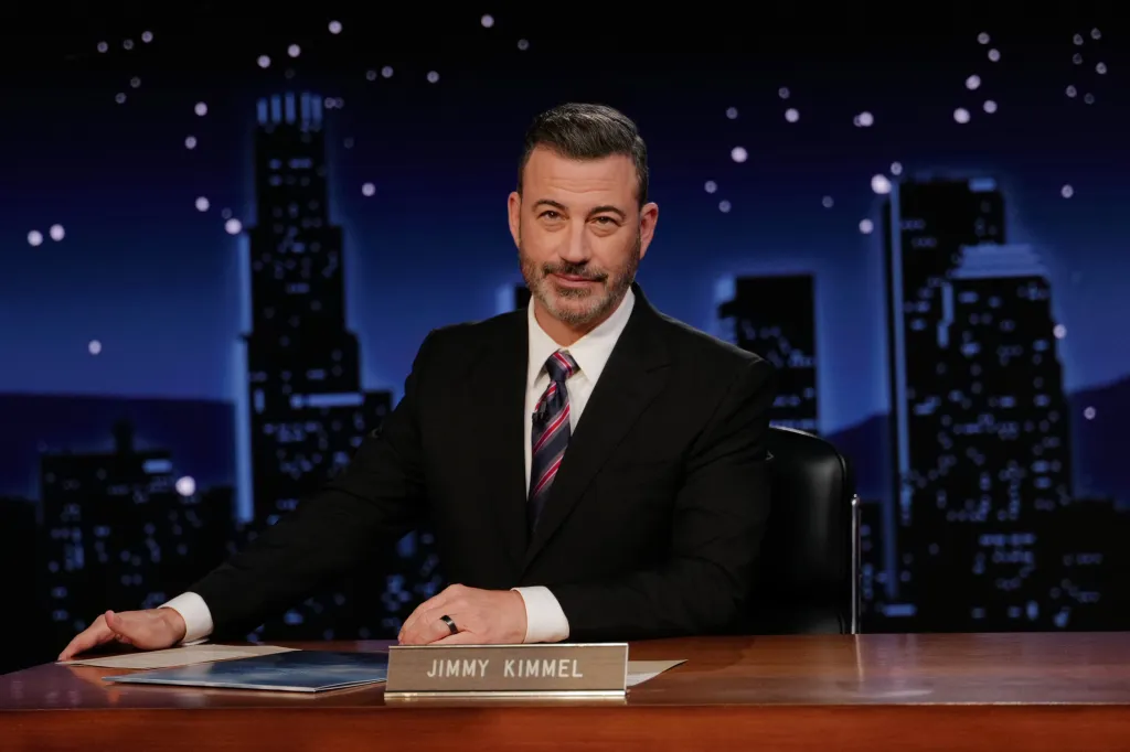Jimmy Kimmel sitting behind a desk with a city skyline backdrop.
