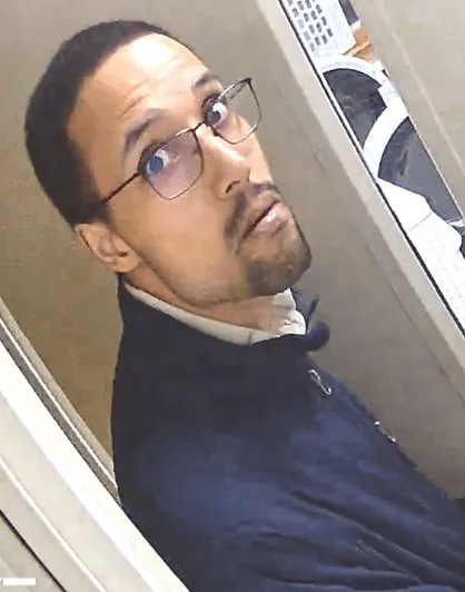 Man with dark hair and glasses looking up and to the left.