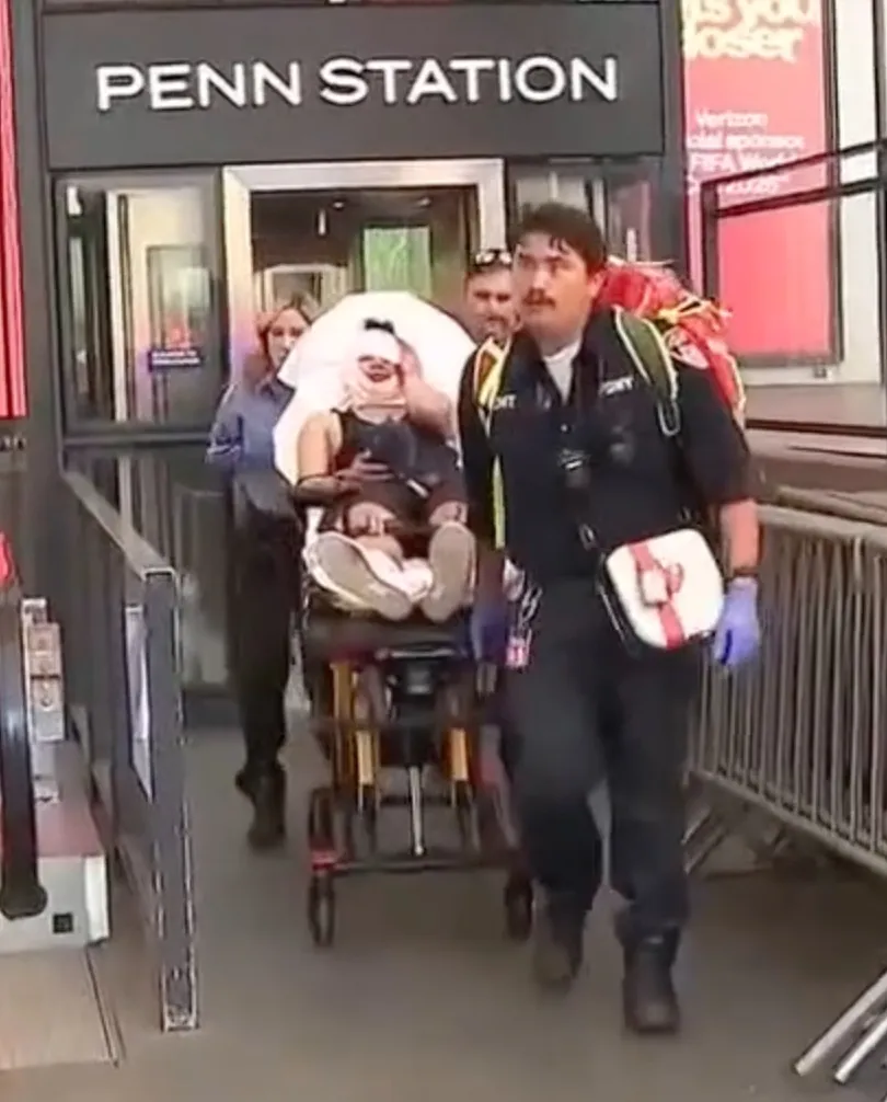 Medical personnel transport a patient on a stretcher at Penn Station.