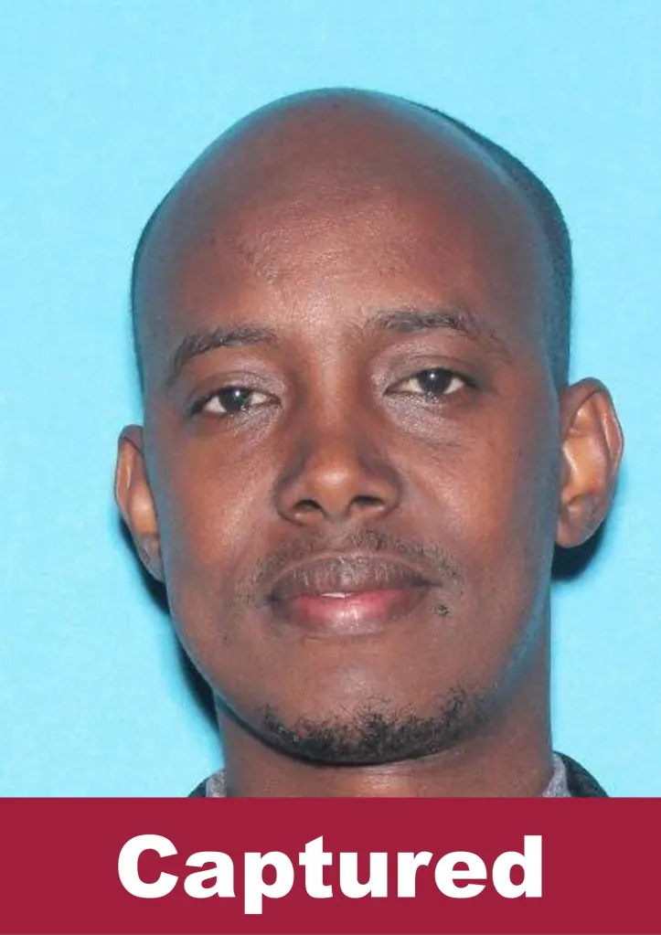 Mugshot of Abdikerm Eidleh, an alleged suspect in a $250M Minnesota fraud case, with "Captured" written across the bottom in white text on a red background.