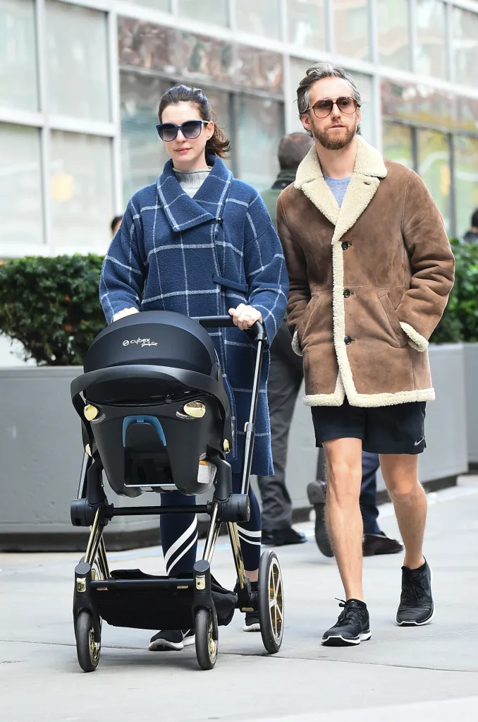 Anne Hathaway pushing a stroller while Adam Shulman walks beside her.