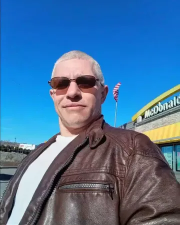 Matt Brown of Alaskan Bush People wearing sunglasses and a leather jacket outside a McDonald's.