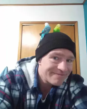 Matt Brown from Alaskan Bush People with two parakeets on his head.