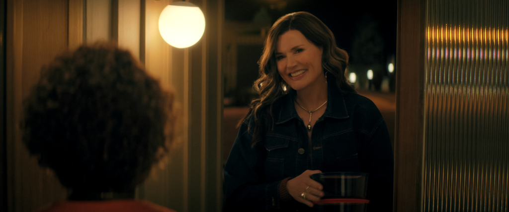 Geena Davis as Renee, smiling while holding a container of food, talking to Alfre Woodard as Judy.