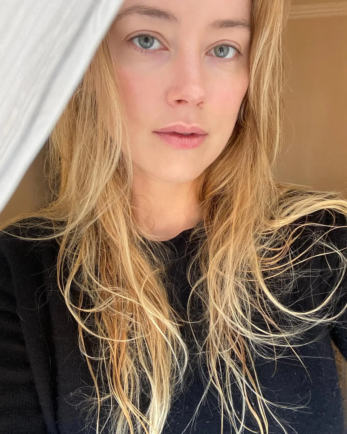 A close-up of Amber Heard's face with her blonde hair cascading over her shoulders.