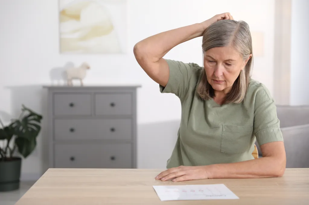 A senior woman with memory loss looking at a paper with numbers, trying to remember something.