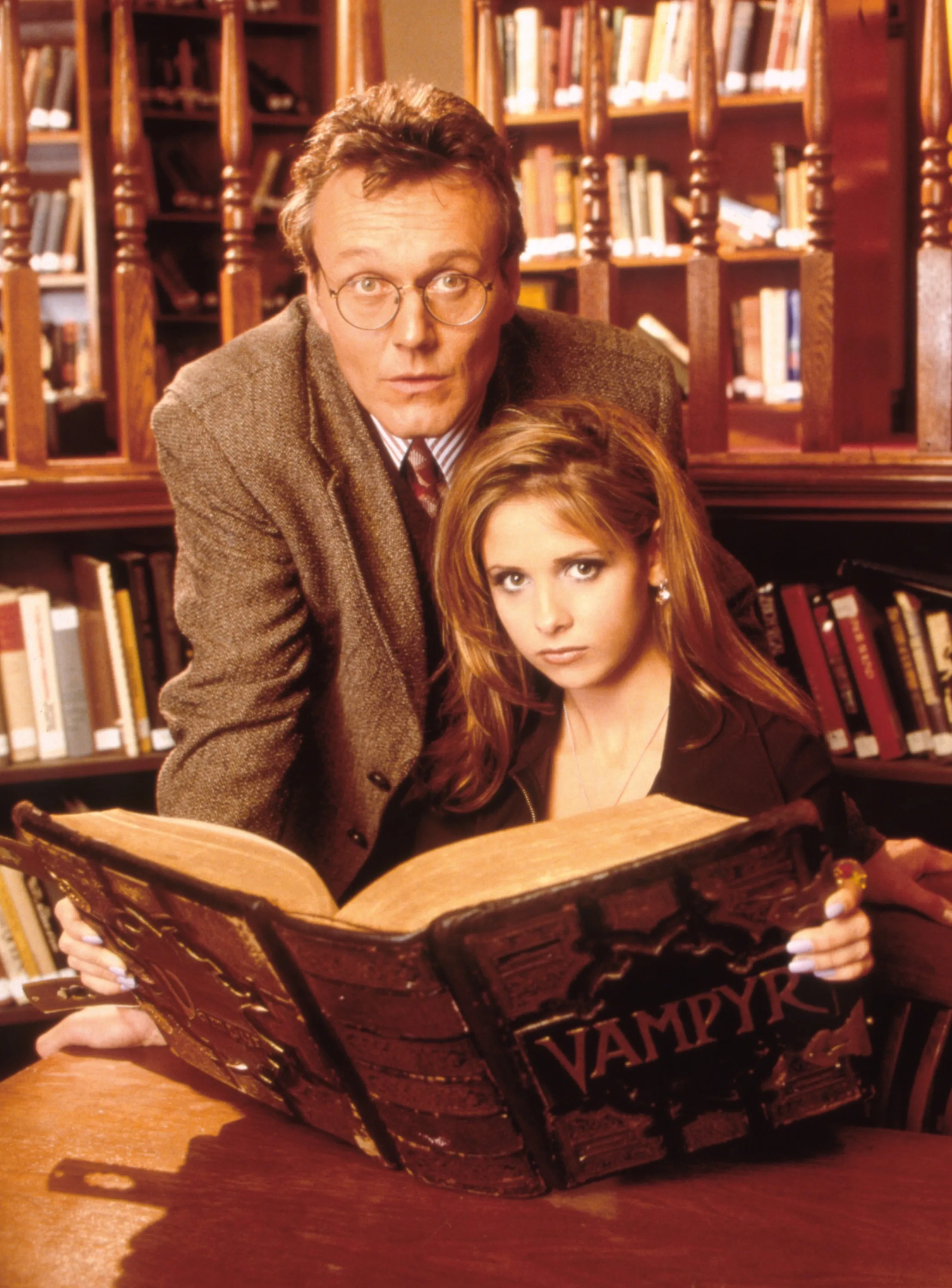 Anthony Stewart Head and Sarah Michelle Gellar looking at a book titled "Vampyr."