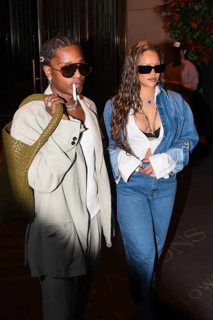 ASAP Rocky and Rihanna walking together, with ASAP Rocky holding a rolled cigarette in his mouth and Rihanna wearing a denim jacket and jeans.
