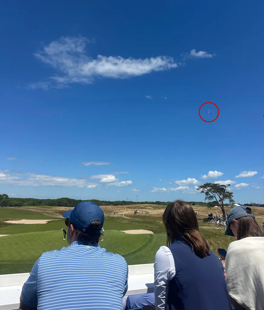 An airplane pulling a banner advertising an abortion pill is seen flying over a golf tournament.