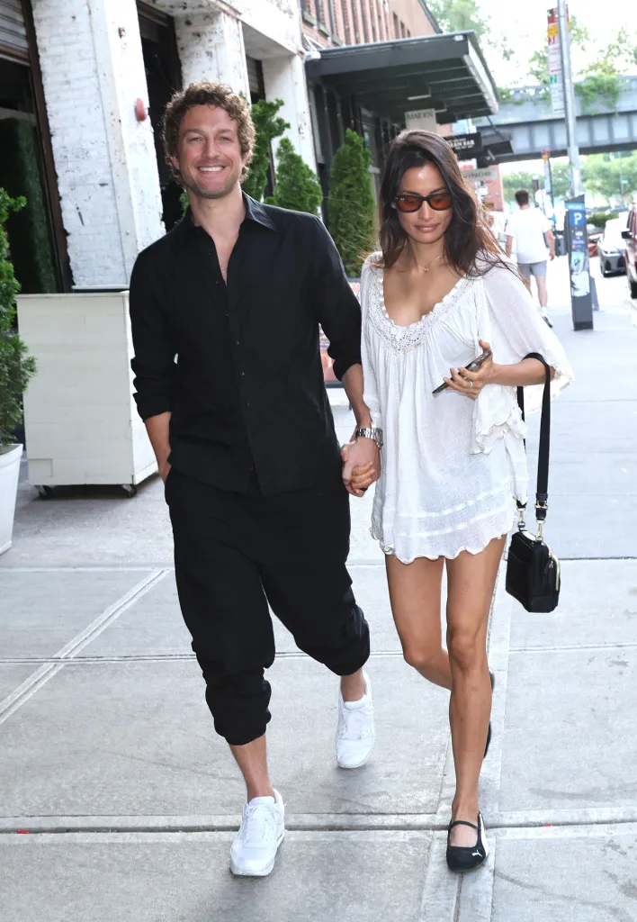 Ben Waddell and Sabrina Belle hold hands while walking down a street in New York City.