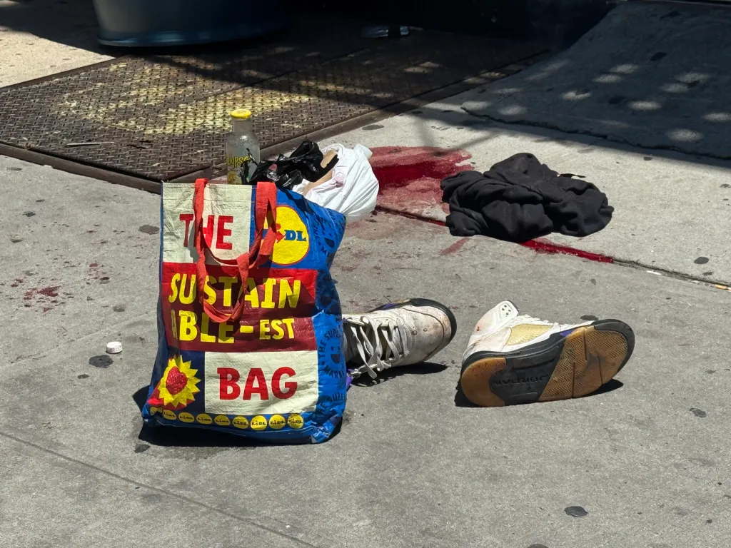 A blood stain, shopping bag and sneakers were still visible on the sidewalk in the aftermath of the shooting.