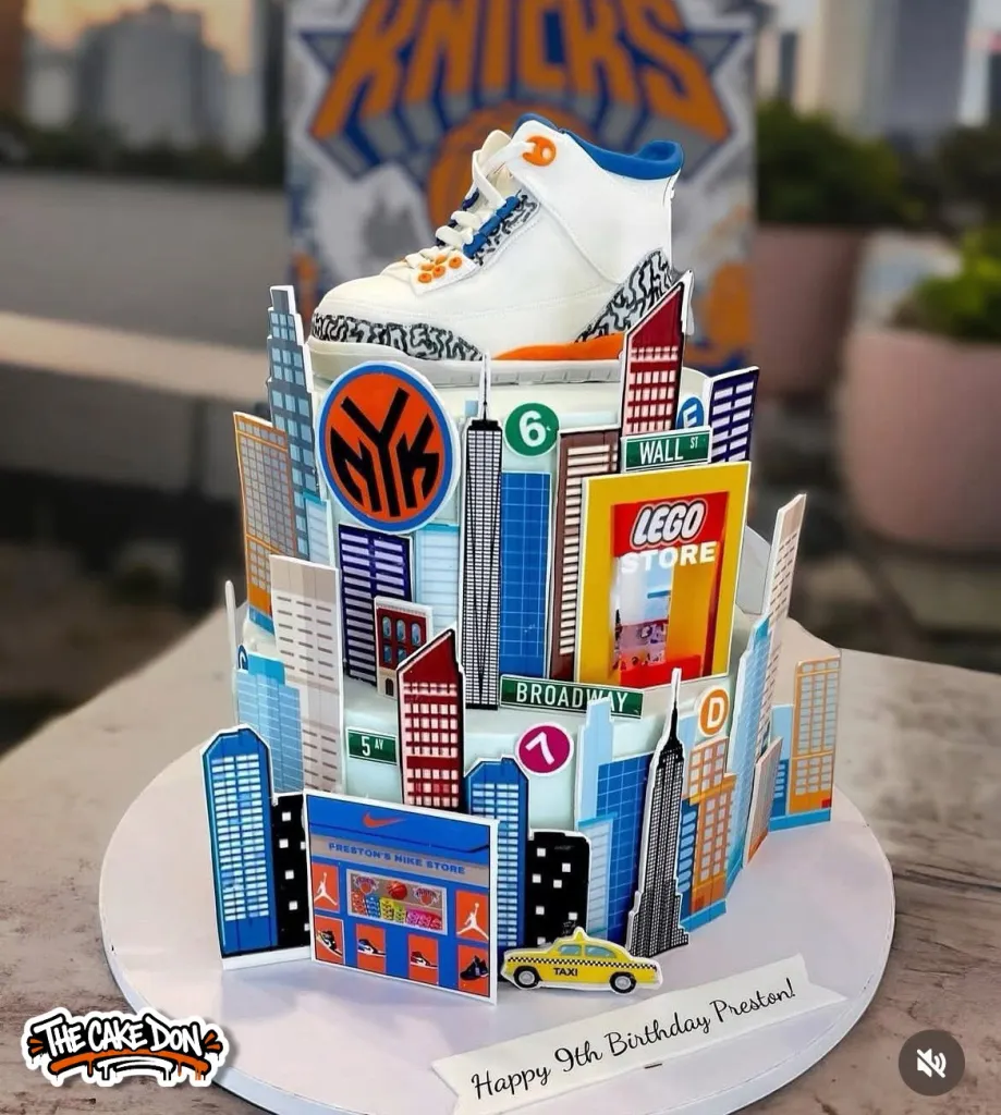 Specialty cake designed as a New York City skyline with a white sneaker on top and a "Happy 9th Birthday Preston!" message.