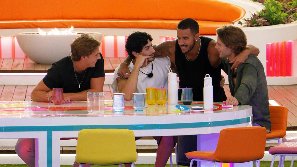 Caleb McDaniel, Zacharias Georgiou, Gabriel Vianna Vasconcelos, and Bryce Alakai Dettloff smiling and interacting at a table.