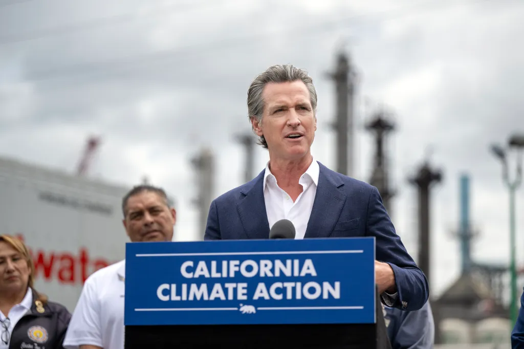 California Governor Gavin Newsom speaking at a "California Climate Action" podium.