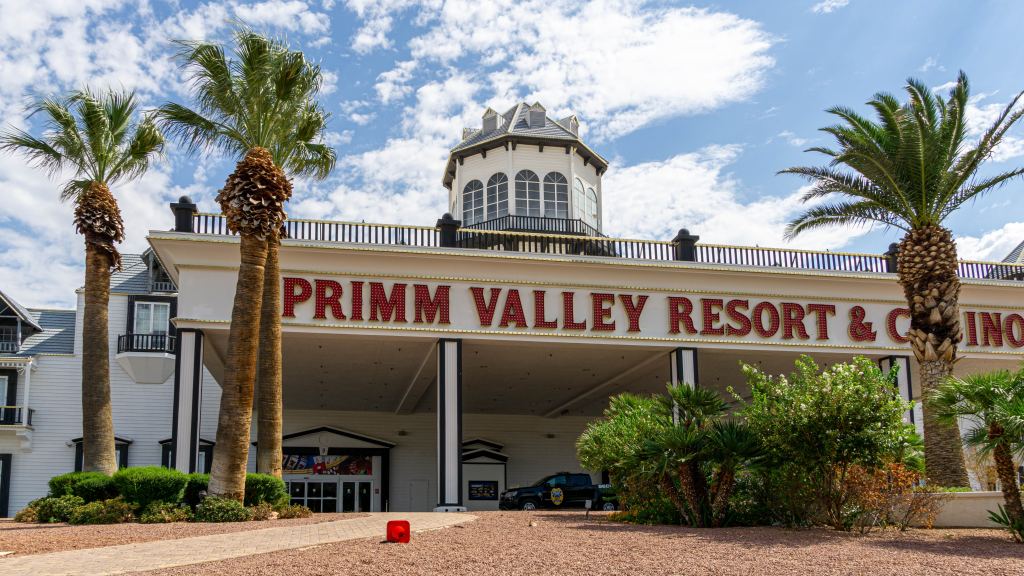 The exterior of Primm Valley Resort & Casino, featuring palm trees and a light blue sky with white clouds.