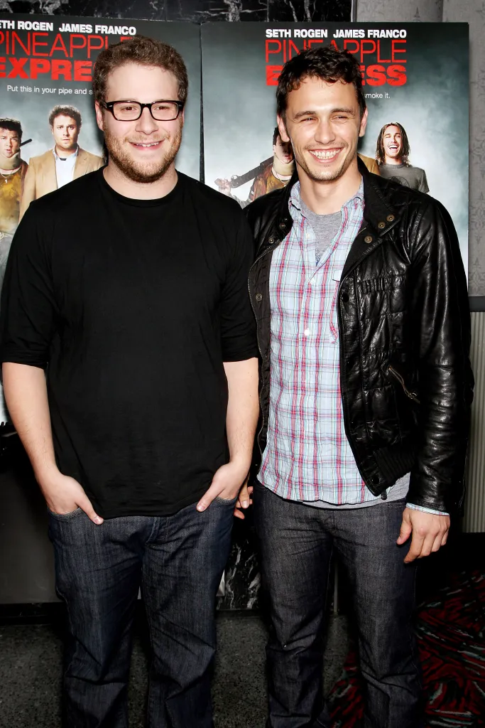 Seth Rogen and James Franco posing in front of a "Pineapple Express" movie poster.