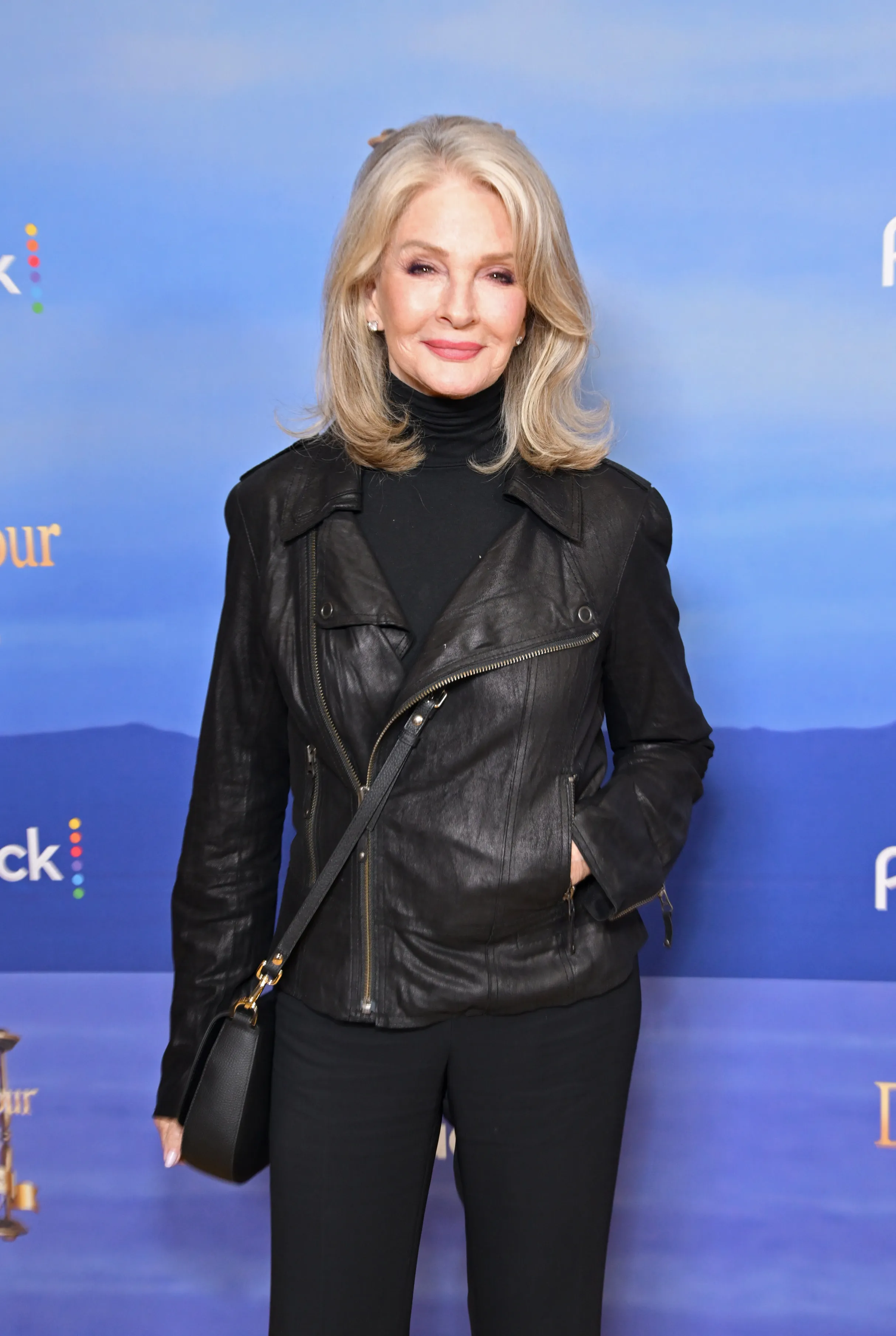 Deidre Hall posing in a black leather jacket and black pants at Peacock's