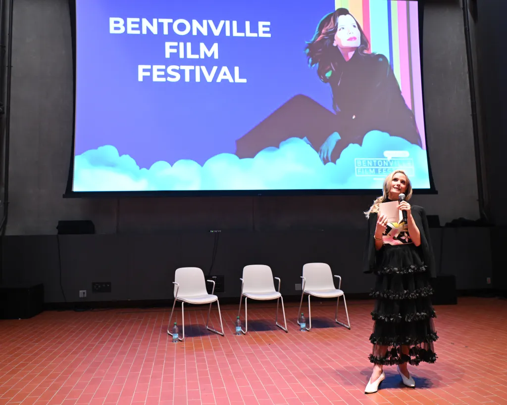 Jennifer Siebel Newsom speaking at the Bentonville Film Festival, with a screen behind her showing "Bentonville Film Festival" and a stylized image of a woman.