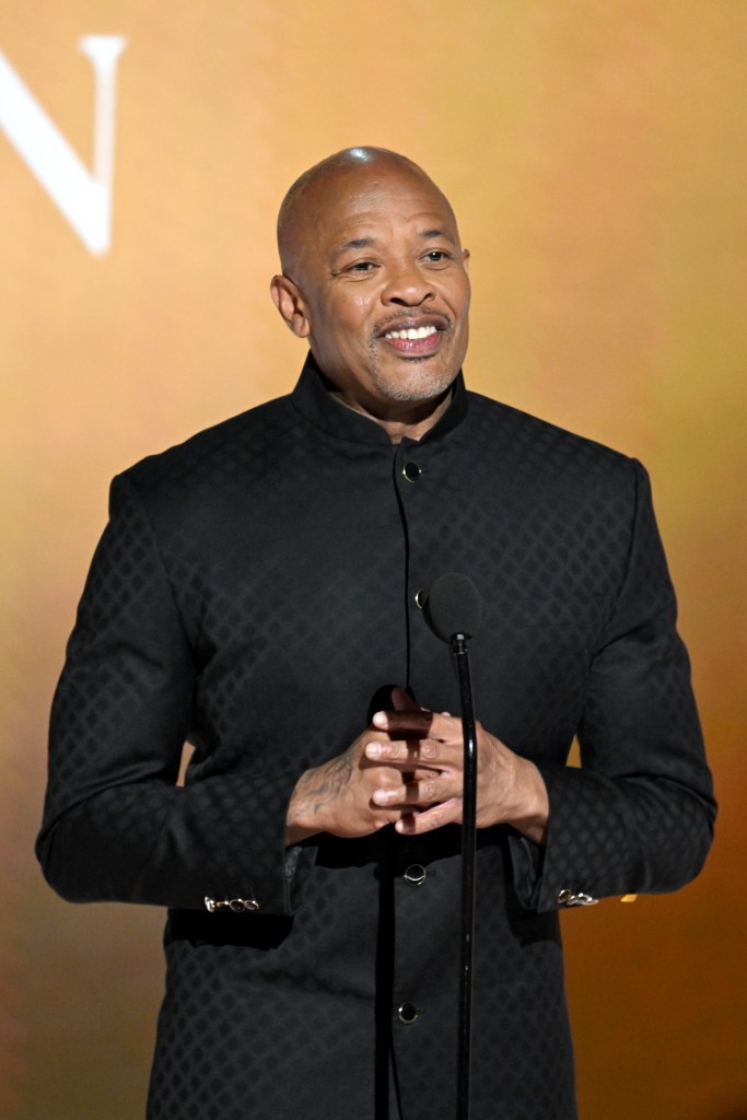Dr. Dre speaks at the 2025 BET Awards, wearing a black patterned jacket, with a microphone in front of him.