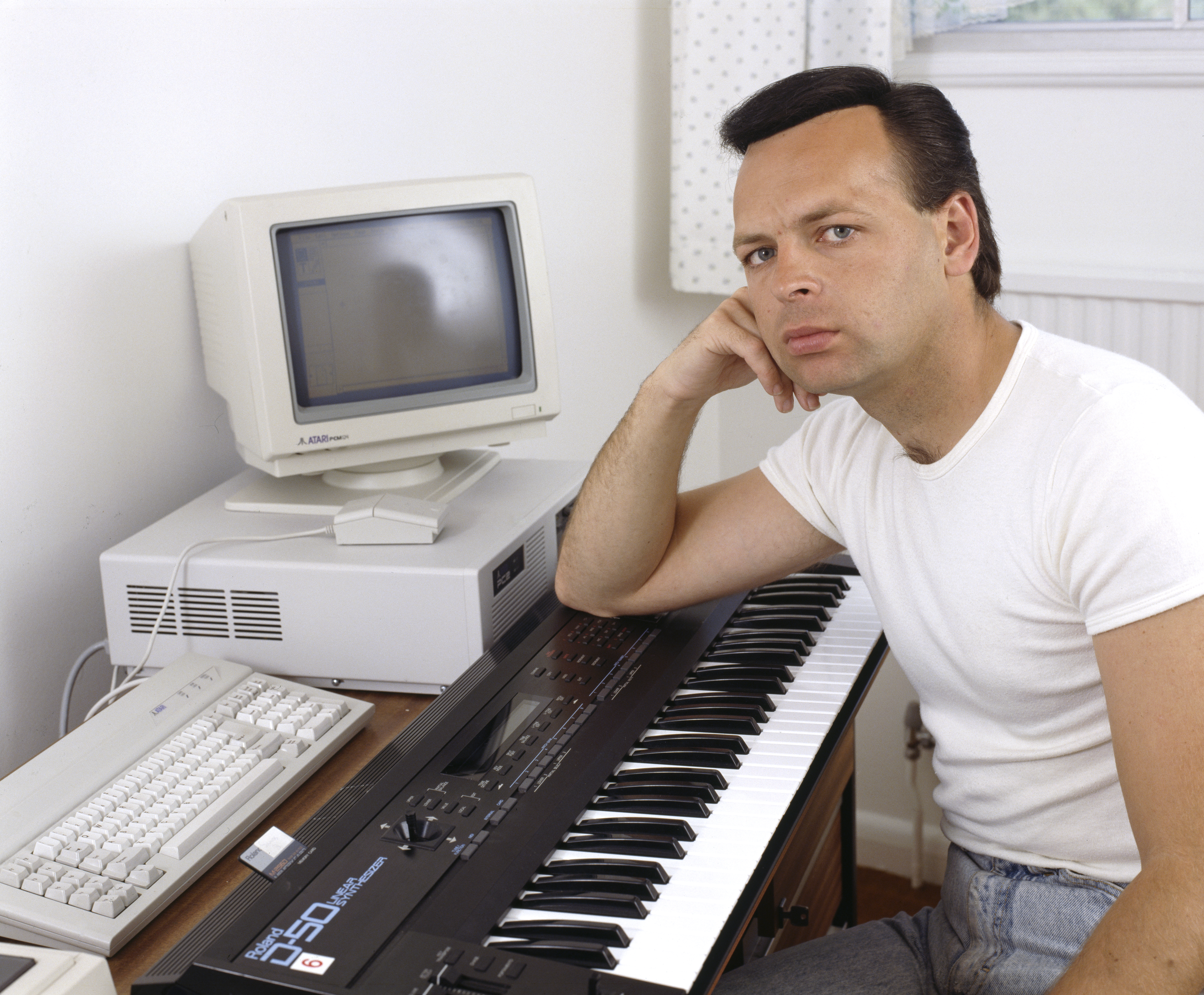 Gary Numan seated with a Roland D-50 synthesizer and computer.
