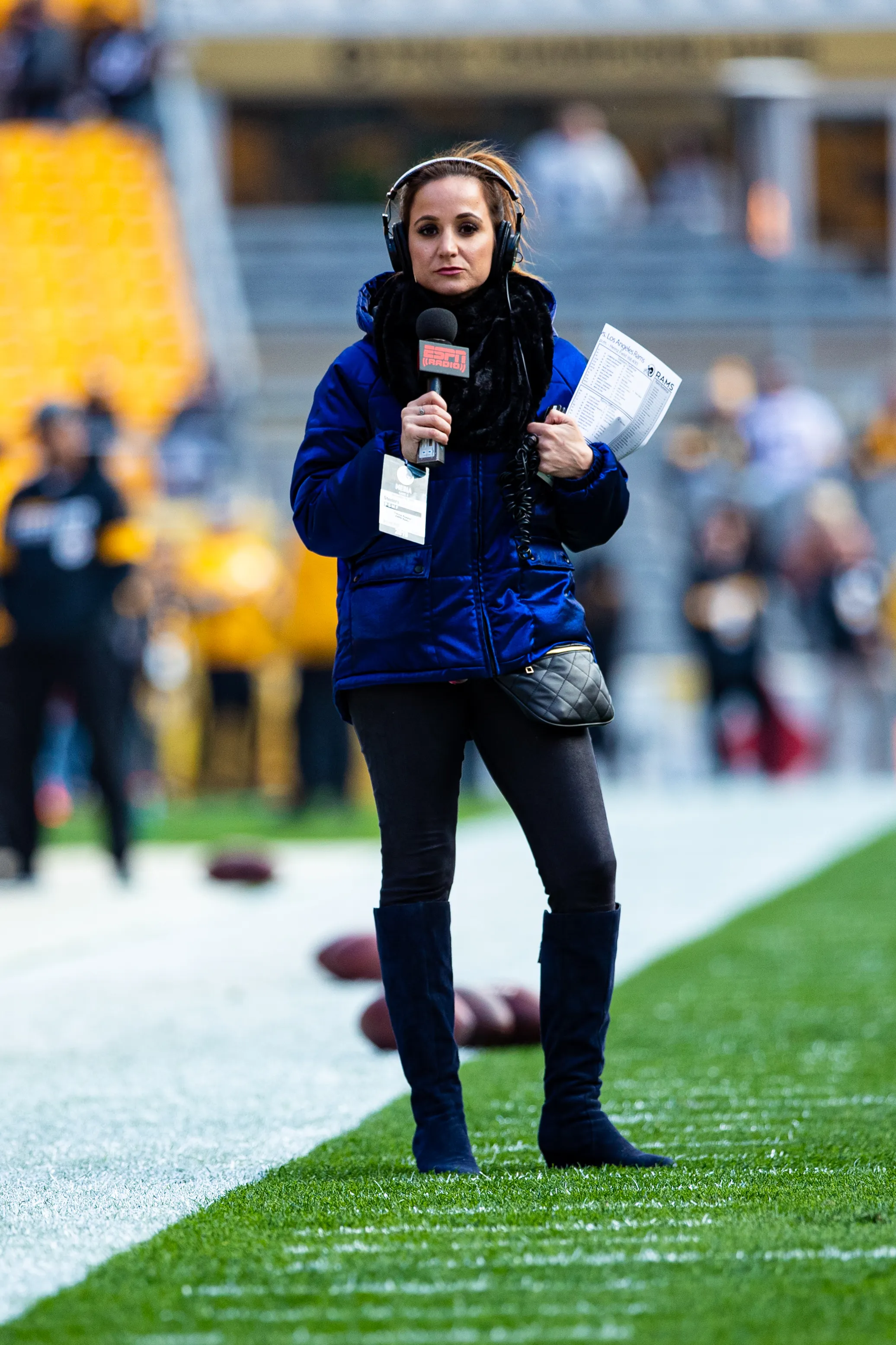 ESPN sideline reporter Dianna Russini on the field with a microphone and notes.