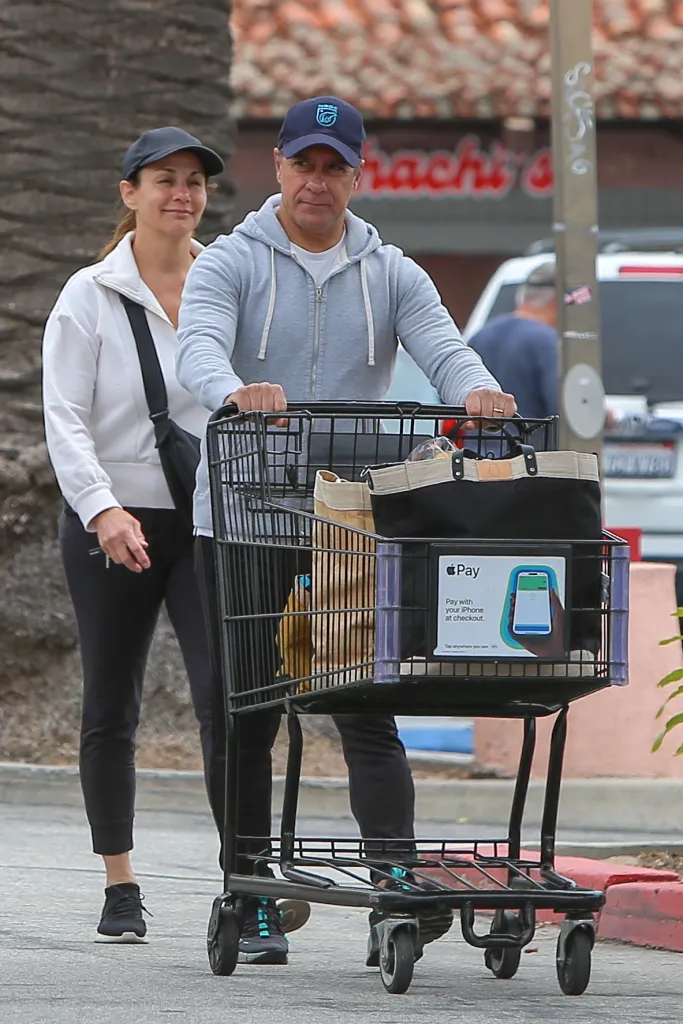 Alberto Carvalho pushing a shopping cart with his wife walking beside him.