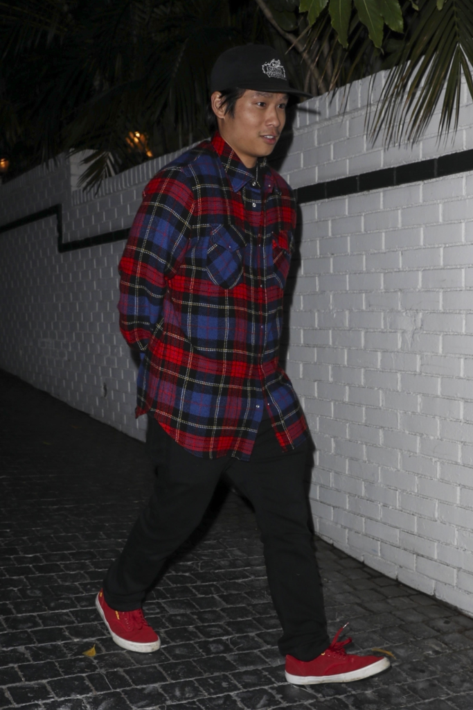 Pax Jolie-Pitt exiting the Chateau Marmont in a red plaid shirt, black pants, and red sneakers.