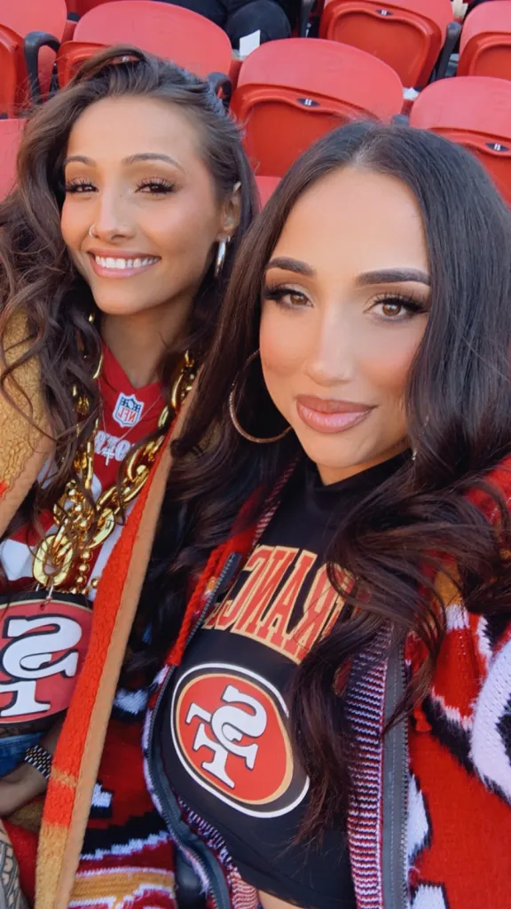 Two women, one identified as Veronica Lopez, smile while wearing 49ers gear in a stadium.