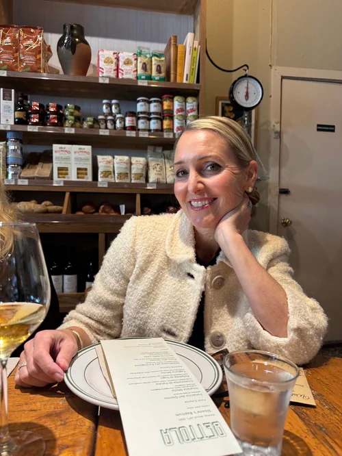Amy Hillyard, a blonde woman, smiling at a restaurant table.
