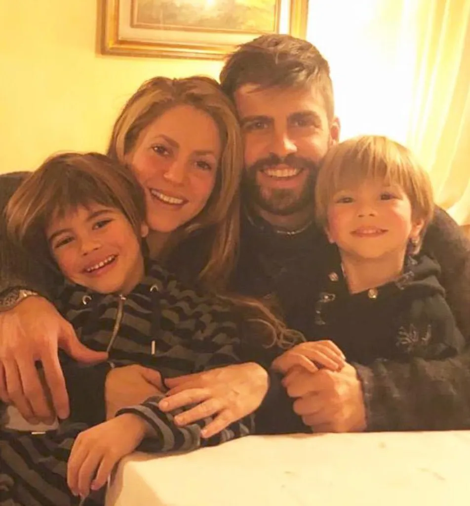 Shakira, Gerard Piqué, and their two children smiling for a family photo.