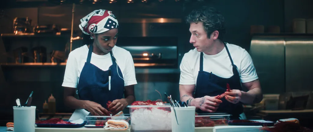 Ayo Edebiri as Sydney Adamu and Jeremy Allen White as Carmen "Carmy" Berzatto preparing food in a kitchen.