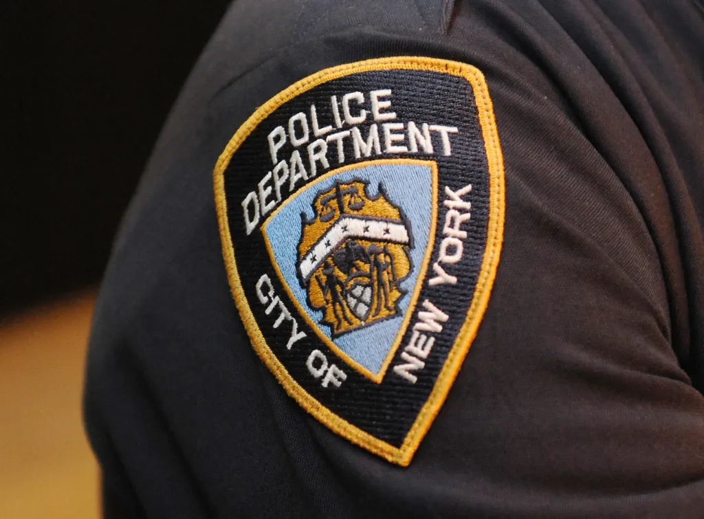 An embroidered NYPD arm patch with a golden border on a navy blue uniform.