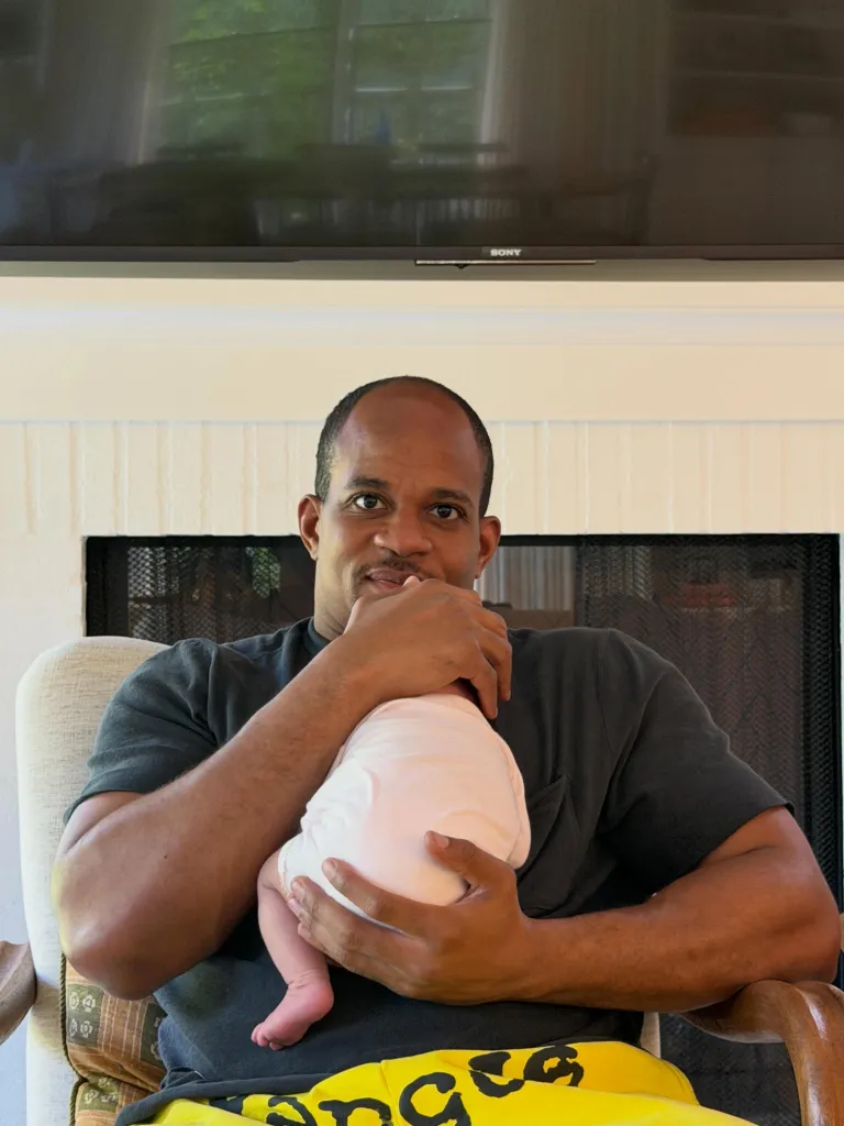 A man holding a baby and looking at the camera.